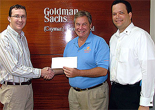 Grant Jackson, Head of the Cayman Office of Goldman Sachs (Cayman) Trust Limited presents his company's cheque to Executive Director of the National Recovery Fund, Dr. Mark Laskin. Also pictured is Goldman Sachs', Chris Bodden.